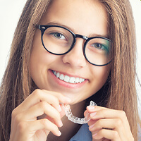 ortho-clear-aligners girl holding up a clear aligner